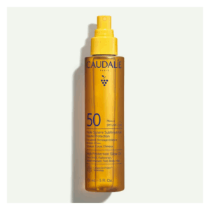 Sonnenöl in einer transparenten Sprühflasche mit gelber Flüssigkeit und Sonnenschutzfaktor 50.